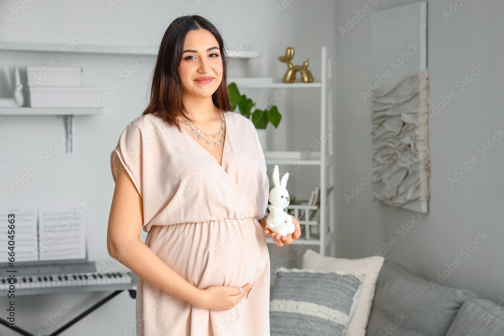 Young pregnant woman with baby toy at home