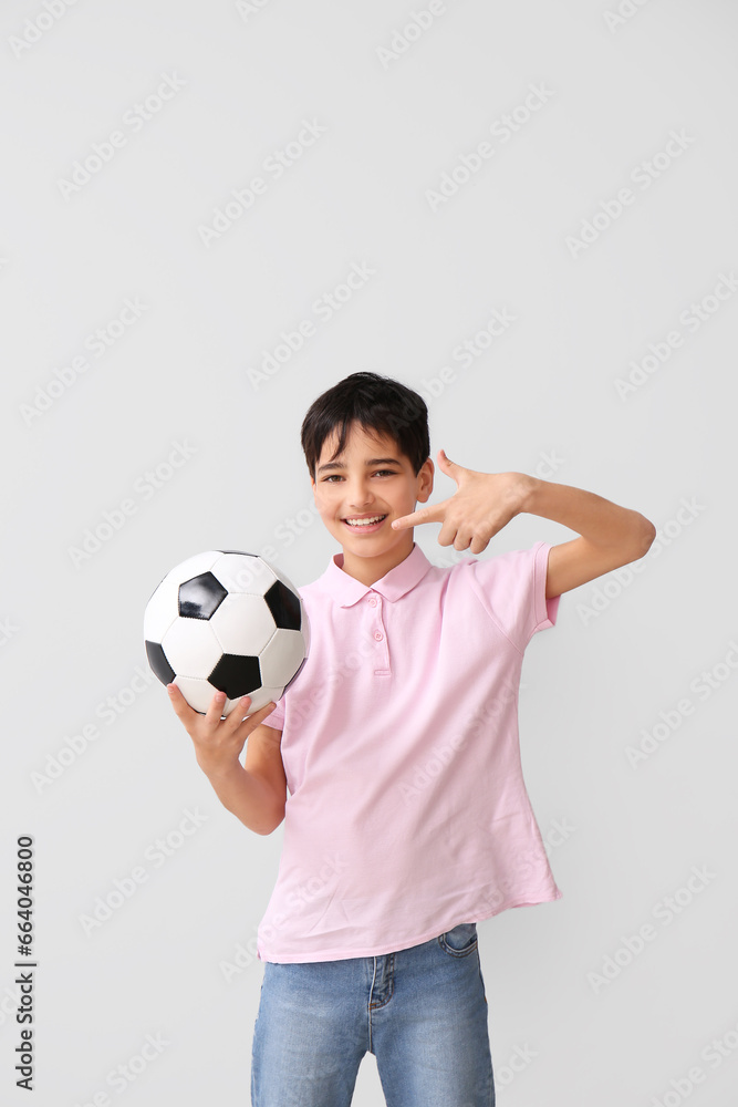 Little boy with soccer ball on grey background