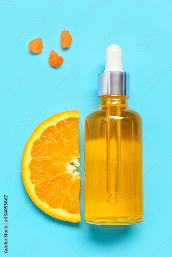 Bottle of citrus essential oil with orange on blue background