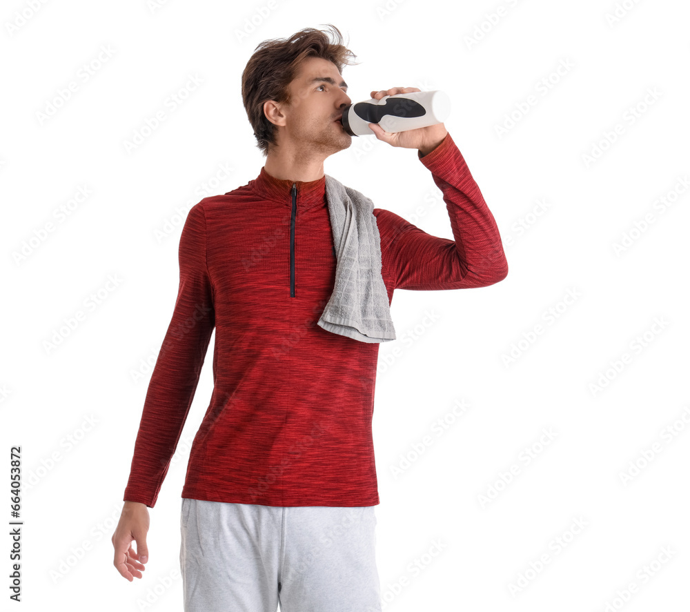 Young handsome man in sportswear drinking water from bottle on white background