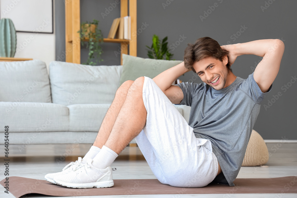 Handsome young man in sportswear swings press at home