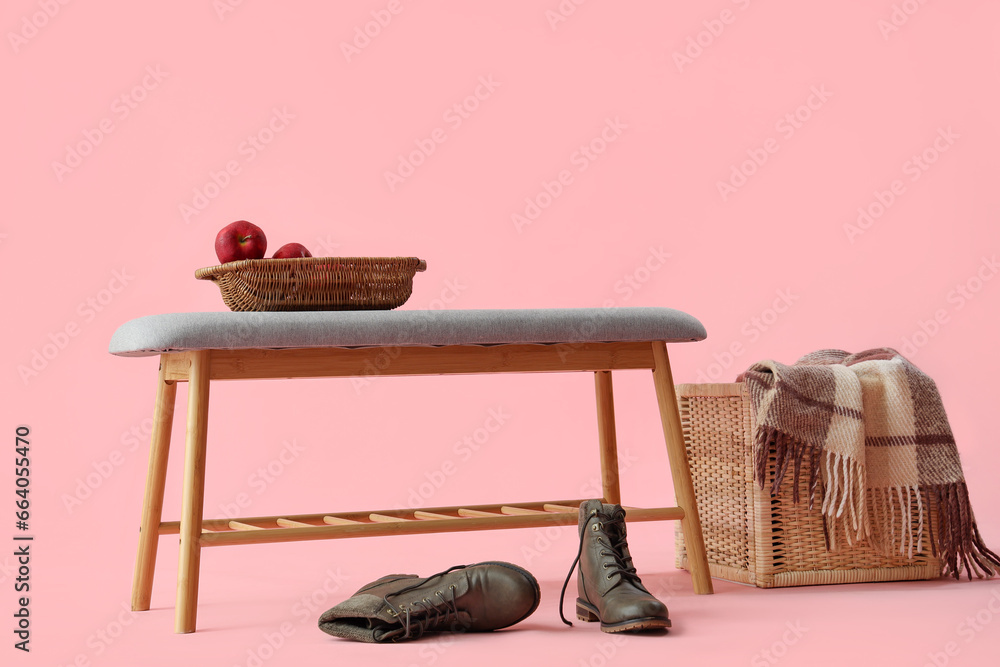 Soft bench with apples, shoes and basket on pink background