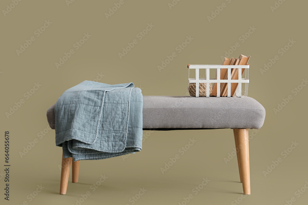 Soft bench with books and plaid on green background