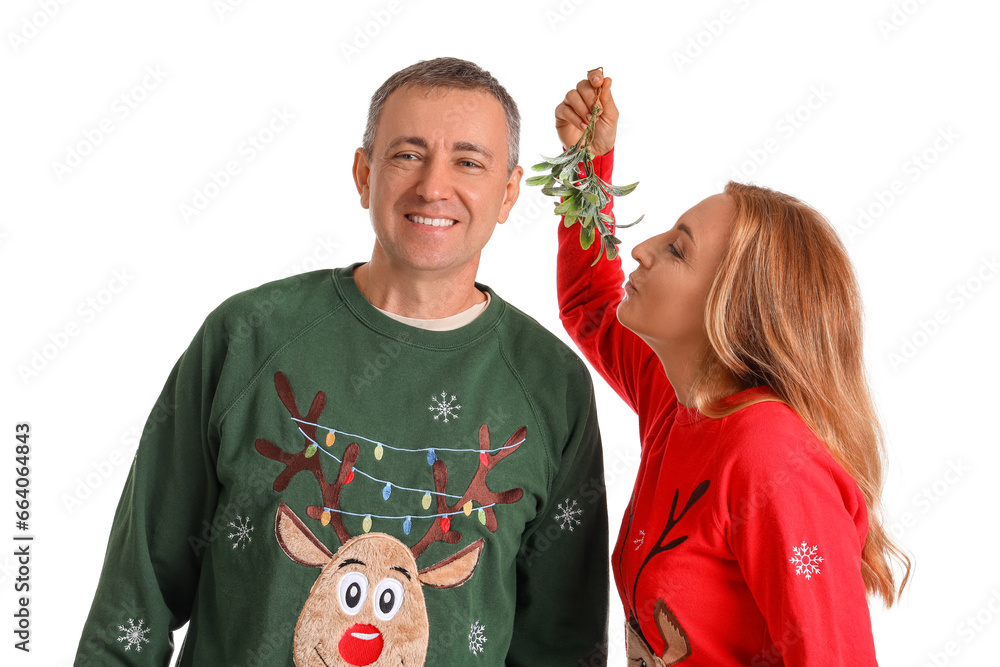 Mature couple kissing under mistletoe branch on white background