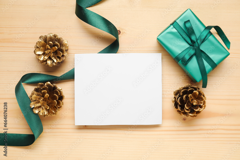 Beautiful Christmas composition with blank card, gift box and pine cones on wooden background