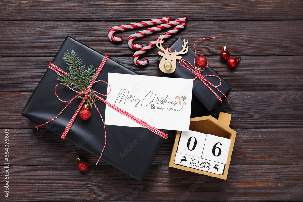 Beautiful Christmas composition with greeting card, gift boxes and decor on black wooden background