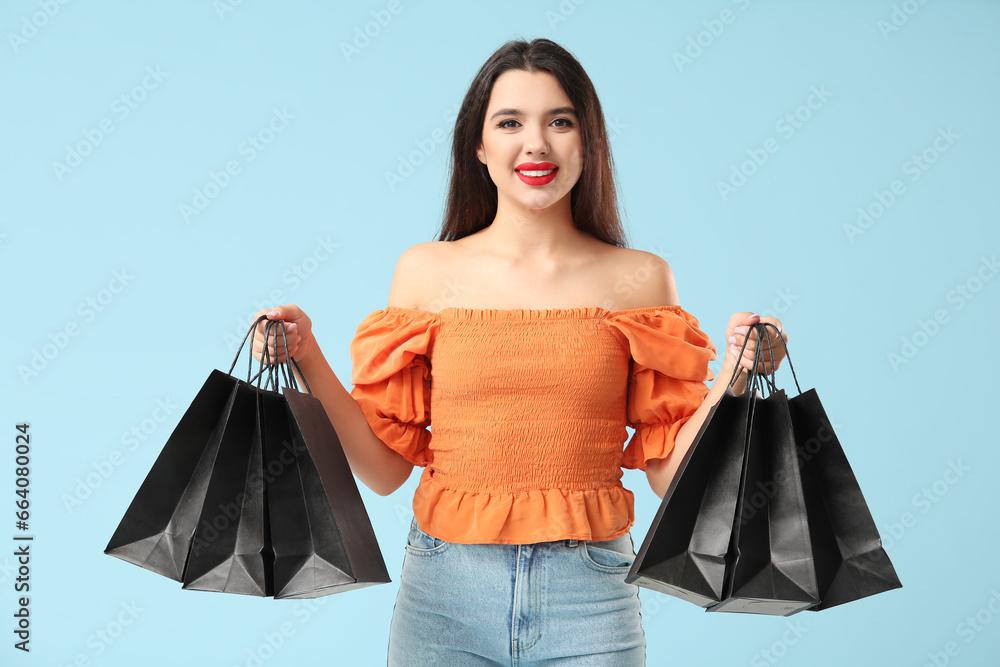 Beautiful woman with shopping bags on blue background. Black Friday sale