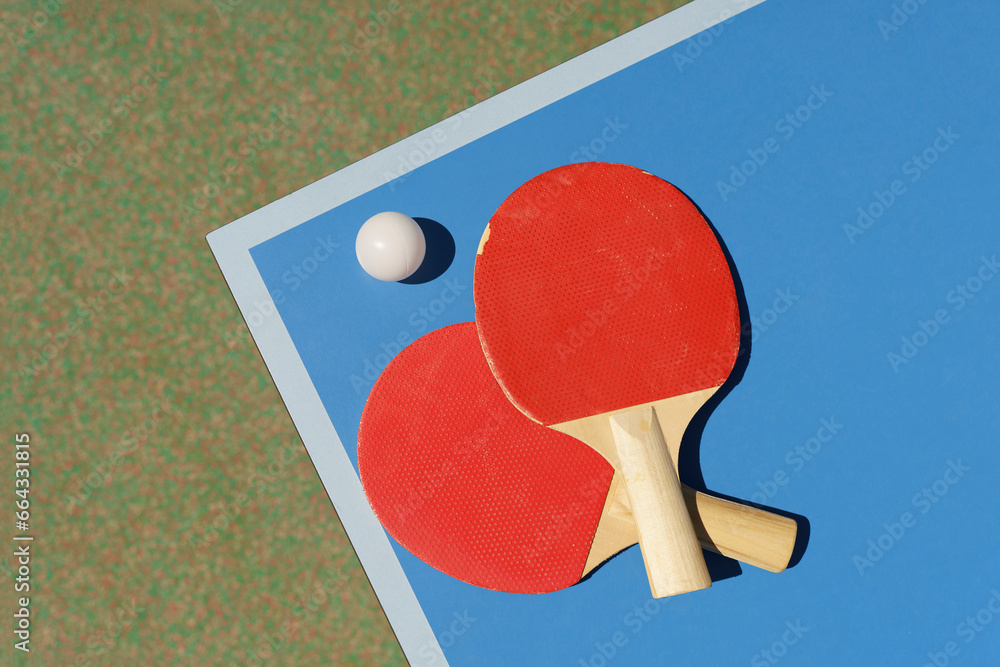 Ping pong tennis table background. Tennis rackets and a ball on a blue sports table.