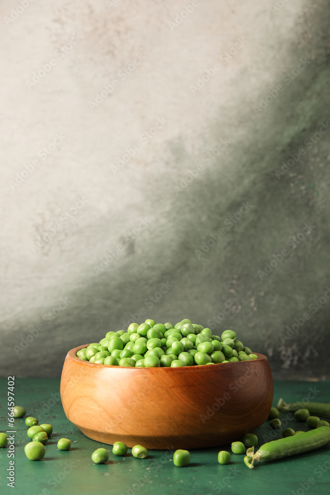 Bowl with fresh green peas on color table