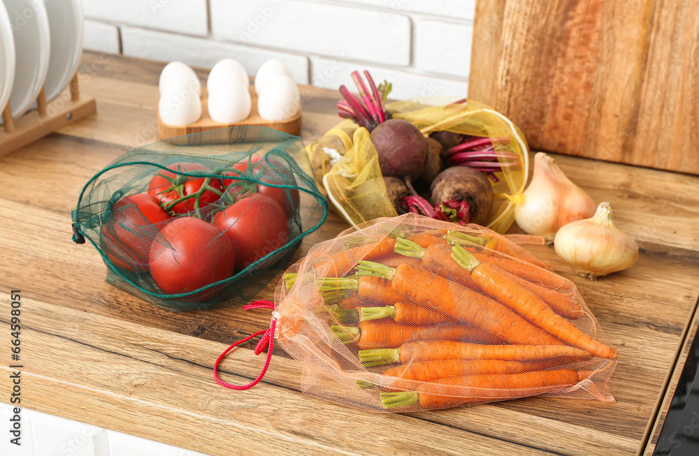 Eco bags with different fresh vegetables on counter in kitchen