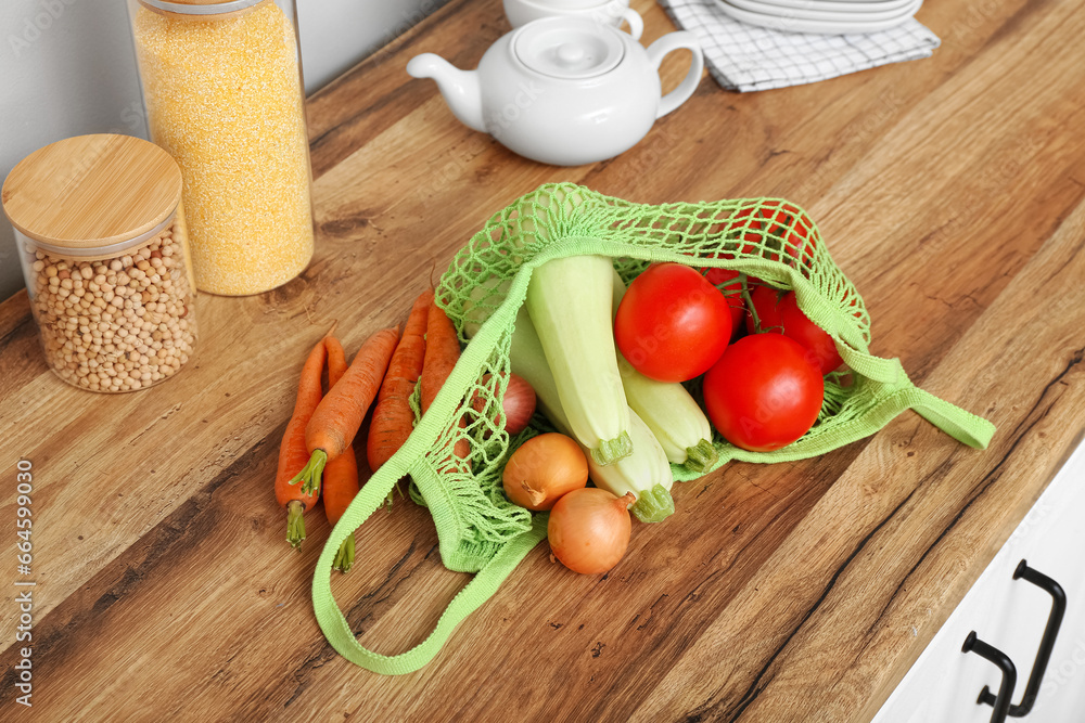 Mesh bag with different fresh vegetables on counter in kitchen