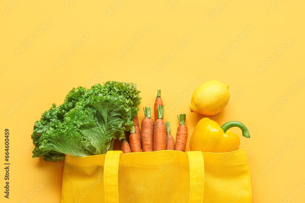 Eco bag with different fresh vegetables on beige background