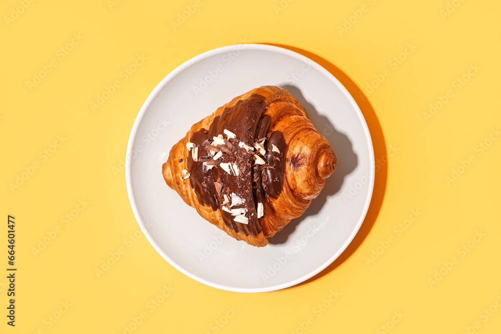 Plate of sweet croissant with chocolate on orange background