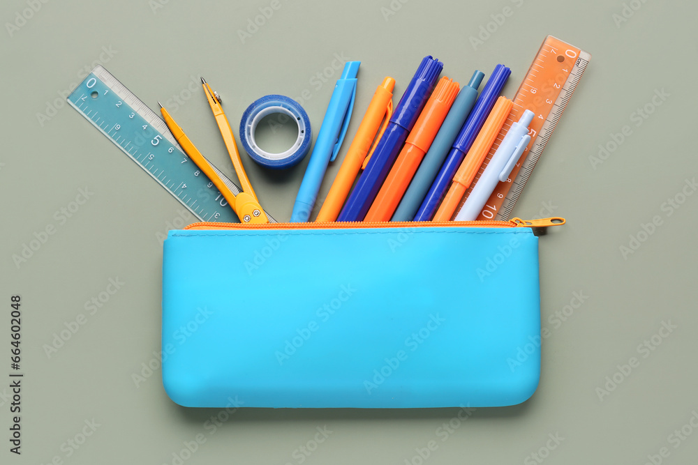 Blue pencil case with school stationery on green background