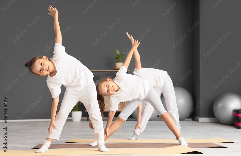 Group of little children practicing yoga in gym