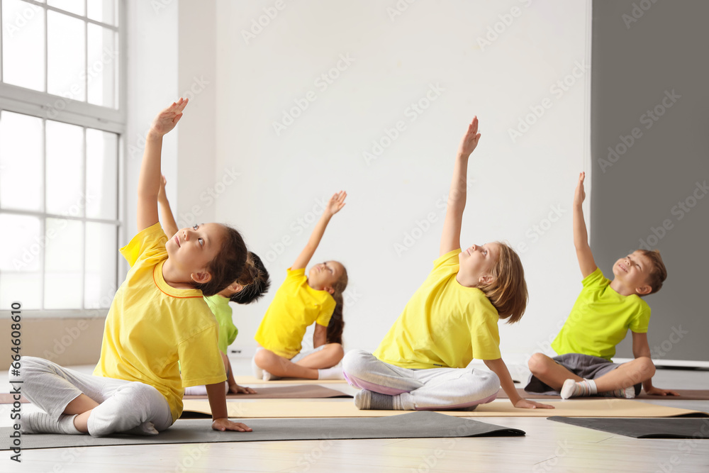 Group of little children practicing yoga in gym