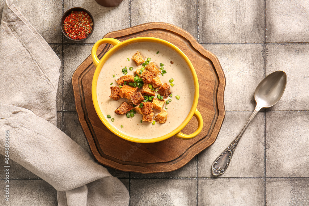 Pot of tasty cream soup with croutons on grey tile background