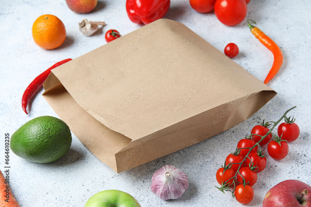 Paper bag and fruits with vegetables on light blue background