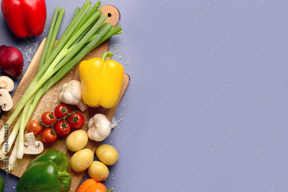 Wooden board with fresh vegetables and mushrooms on blue background