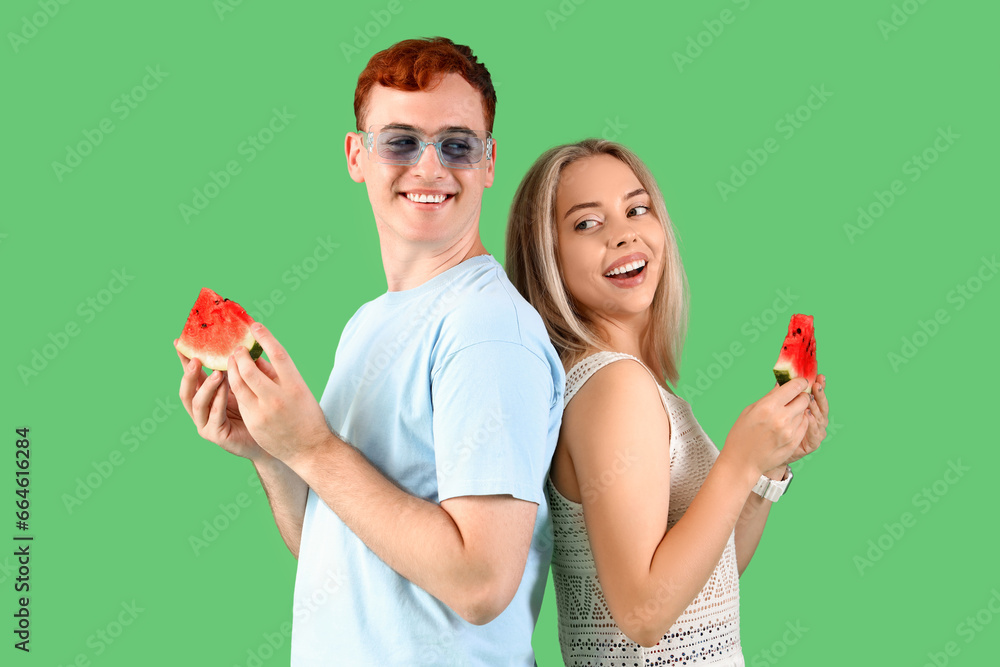 Young beautiful man and woman with slices of fresh watermelon on green background