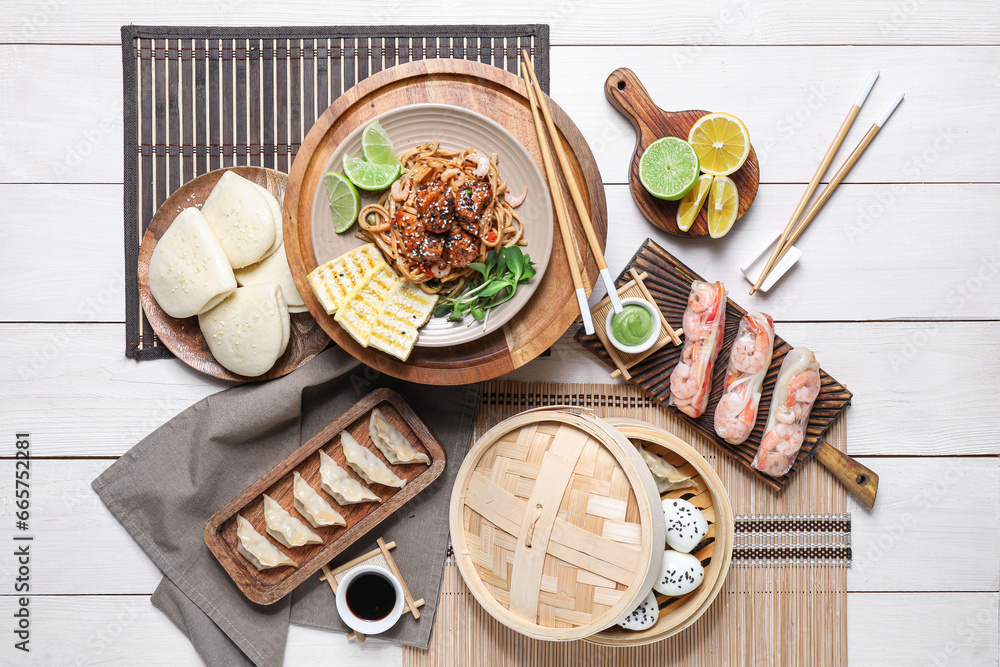 Composition with different Chinese dishes and chopsticks on light wooden background