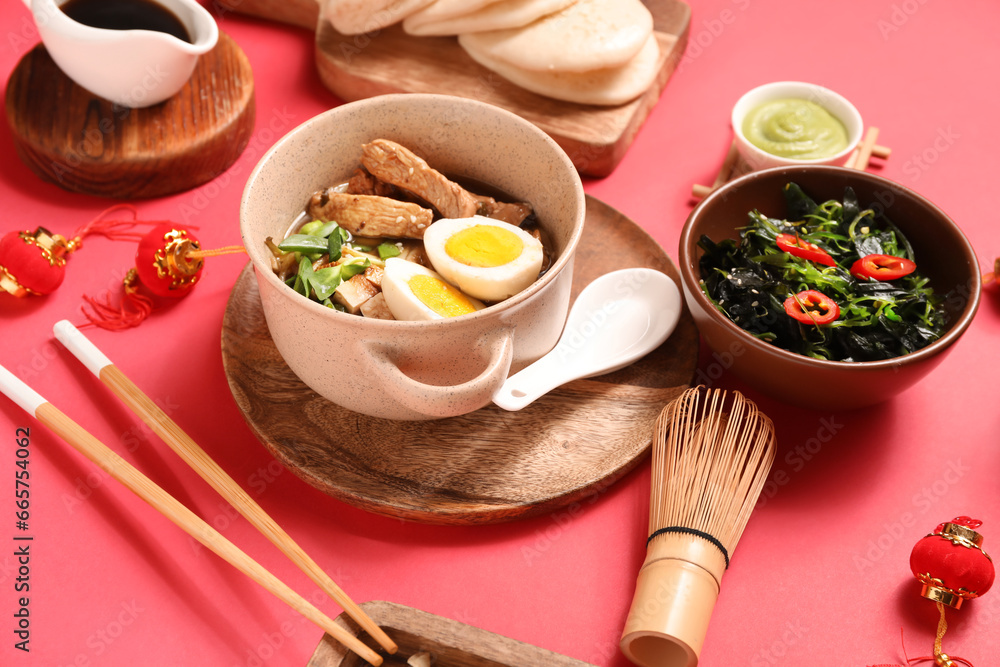 Composition with tasty Chinese dishes and decor on red background