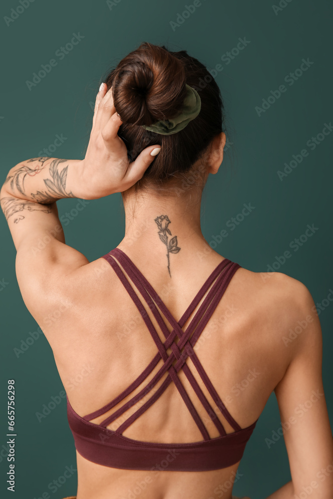 Tattooed young woman on green background, back view