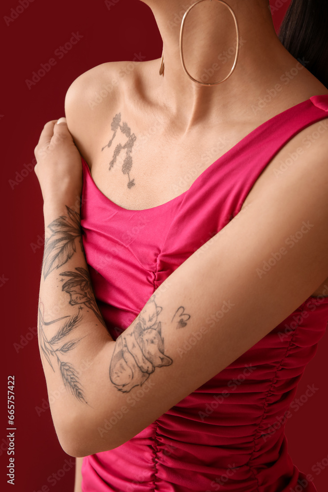 Tattooed young woman on pink background, closeup