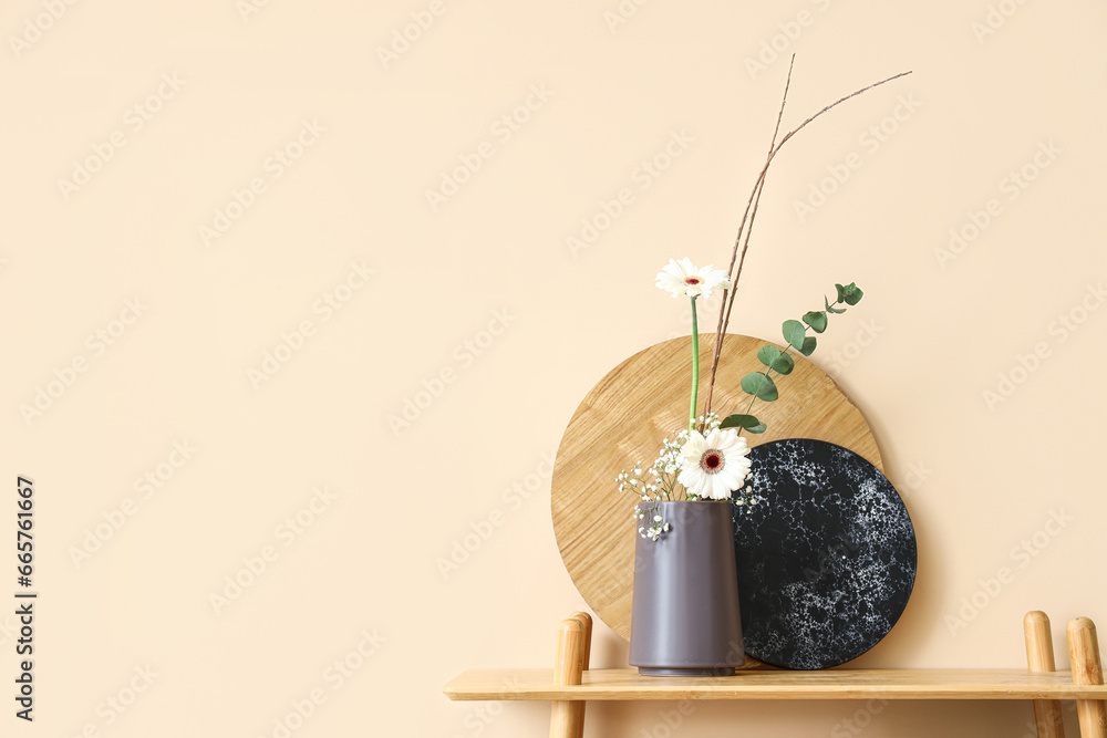 Beautiful ikebana on shelf near beige wall