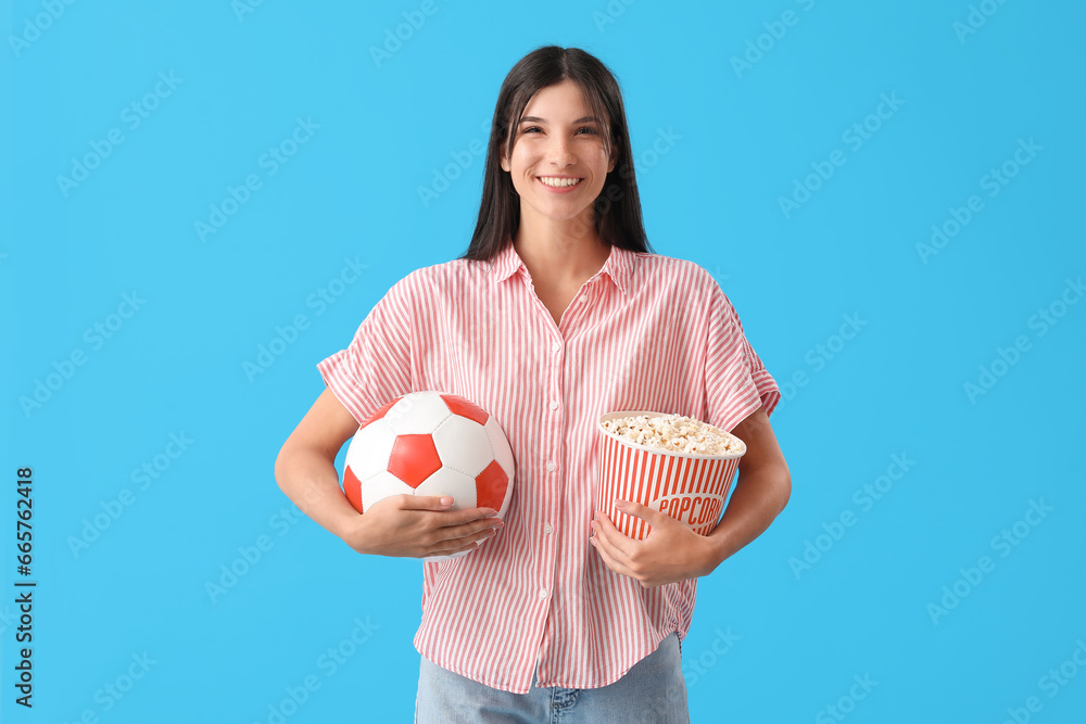 Female soccer fan with popcorn and ball on blue background