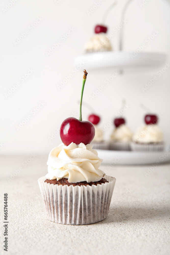 Tasty cherry cupcake on light background