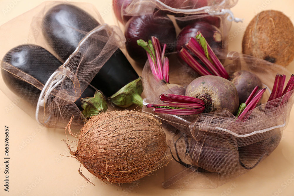 Eco bags with different fresh products on beige background, closeup