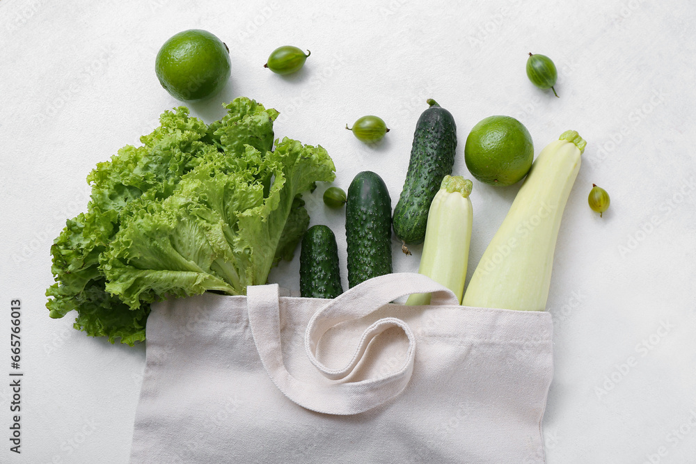 Eco bag with different fresh vegetables on light background