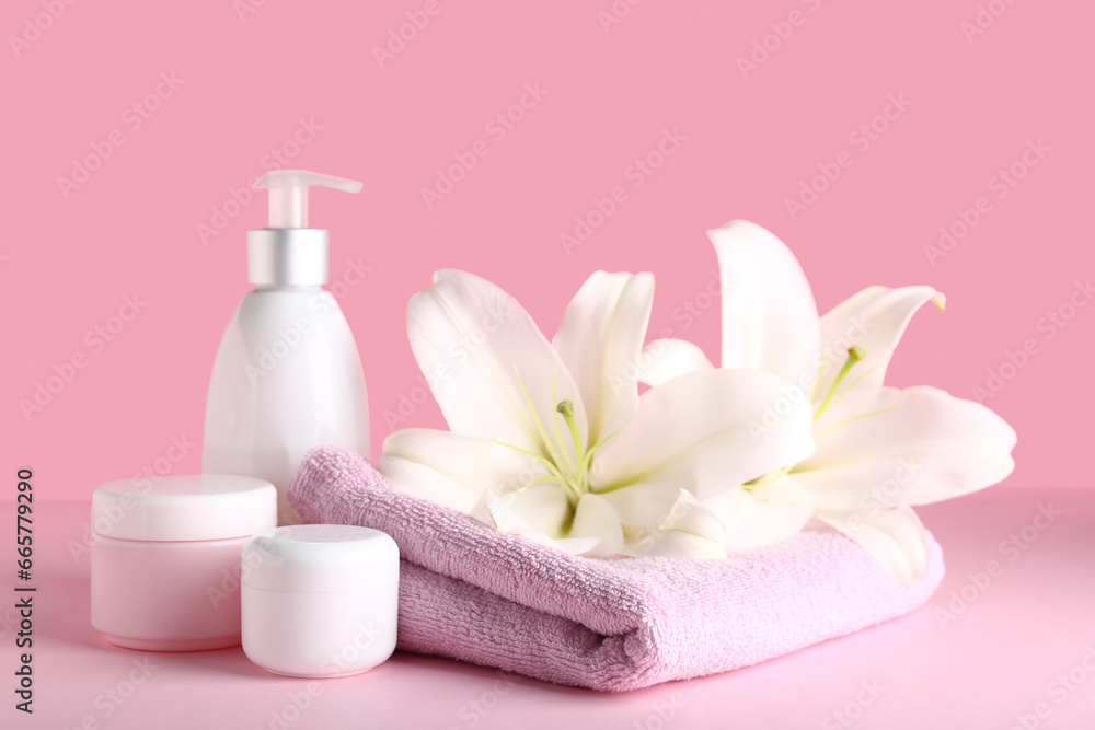 Set of cosmetic products, clean towel and beautiful lily flowers on pink background