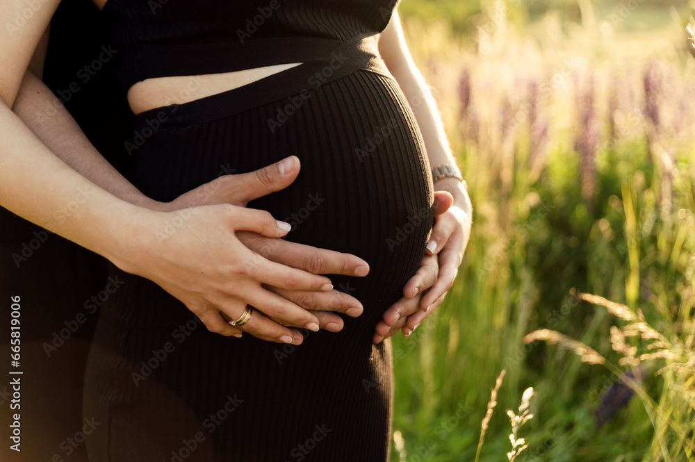 a mans hands hug a pregnant womans belly. cropped photo. pregnancy and happy family concept