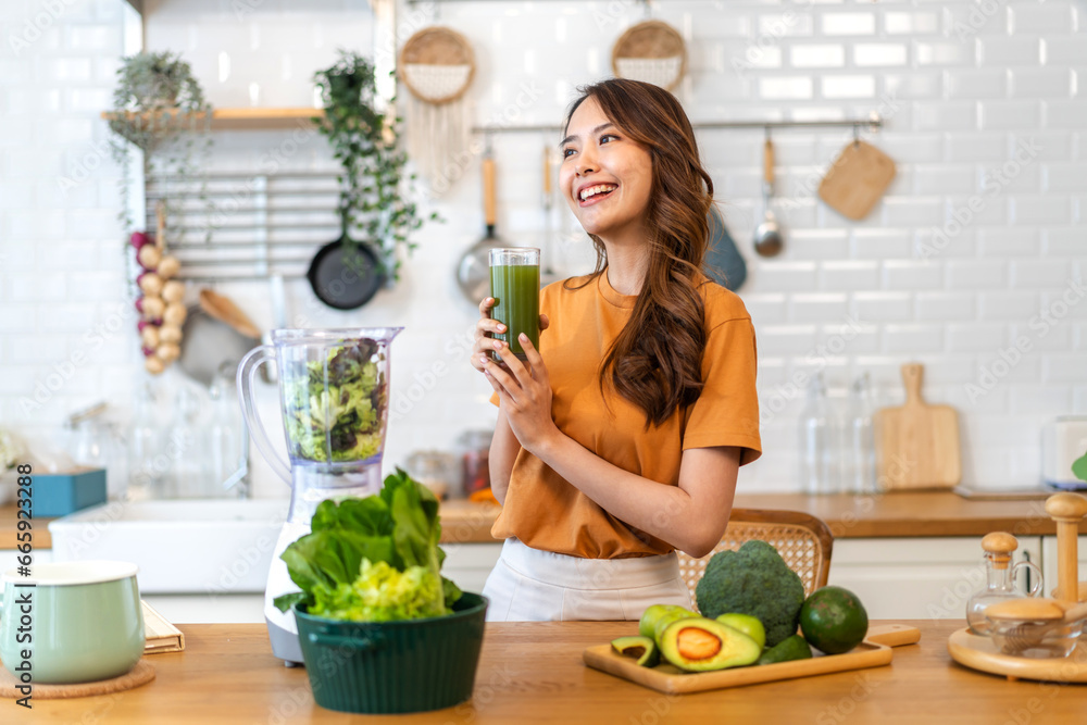 Portrait of beauty healthy asian woman making green vegetables detox cleanse and green fruit smoothie with blender.young girl drinking glass of smoothie, fiber, chlorophyll in kitchen.Diet, healthy