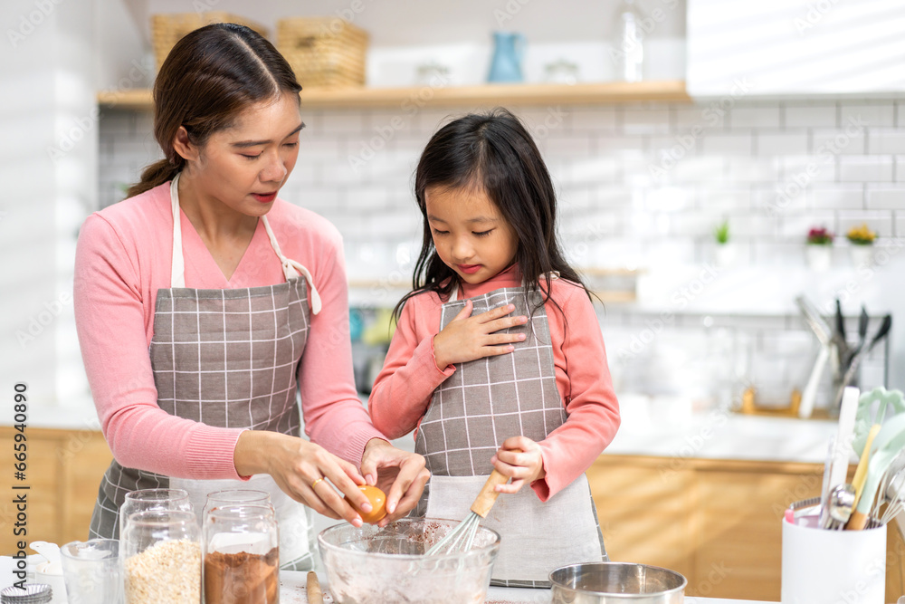 Portrait of enjoy happy love asian family mother and little toddler asian girl daughter child having fun cooking together with dough for homemade bake cookie and cake ingredient on table in kitchen