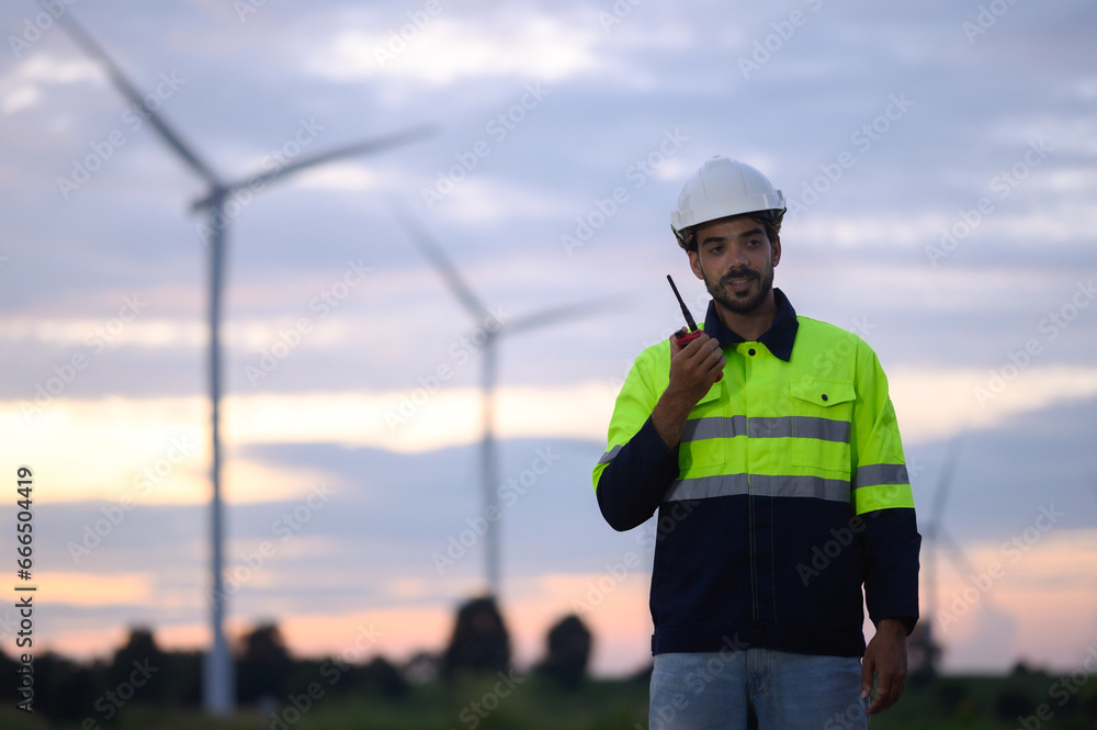 Portrait of engineer wearing yellow vest and white hat on site at wind farm or solar cell farm and energy sustainable energy concept