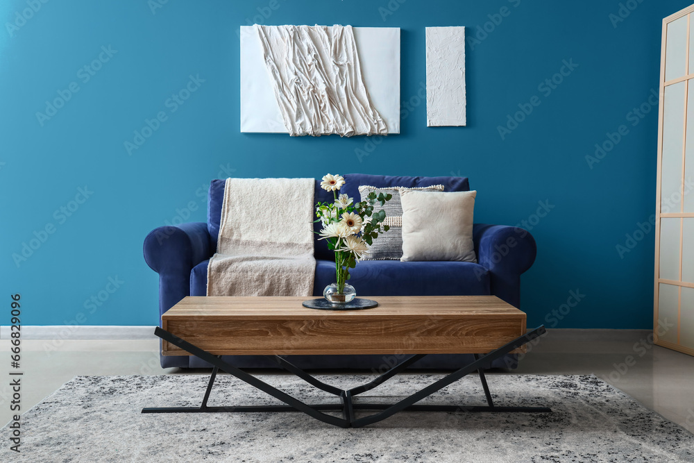 Interior of living room with ikebana on table and blue sofa