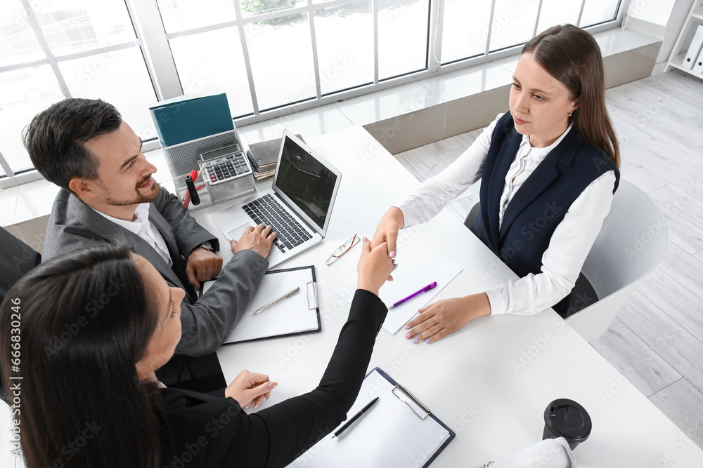 Human resources manager shaking hands with female applicant in office