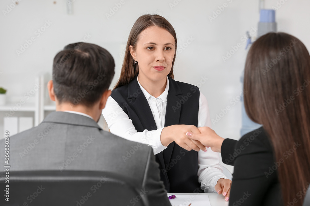 Human resources manager shaking hands with female applicant in office