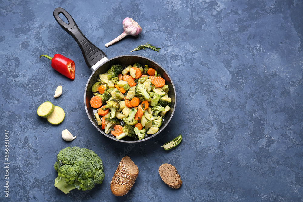 Frying pan with tasty vegetables on blue background