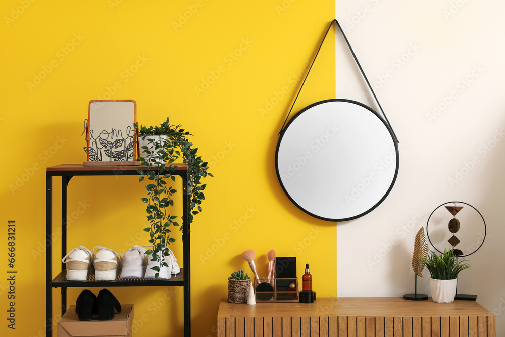 Interior of stylish hallway with mirror, wooden cabinet and shoe stand