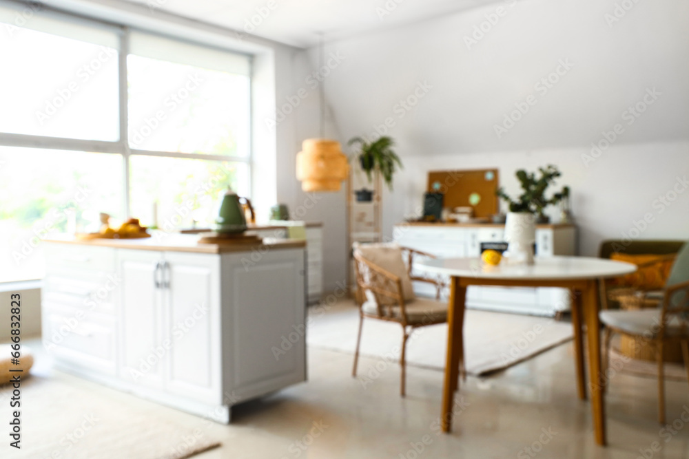 Interior of modern kitchen with white counters and dining table