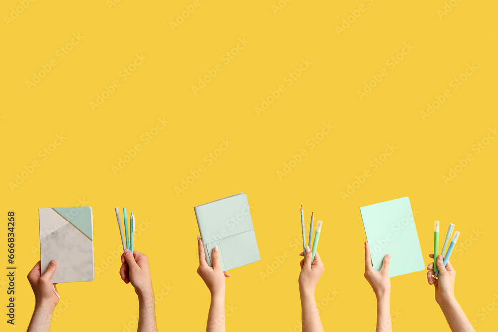 Hands with school supplies on yellow background