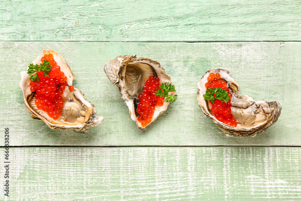 Tasty oysters with red caviar on green wooden background