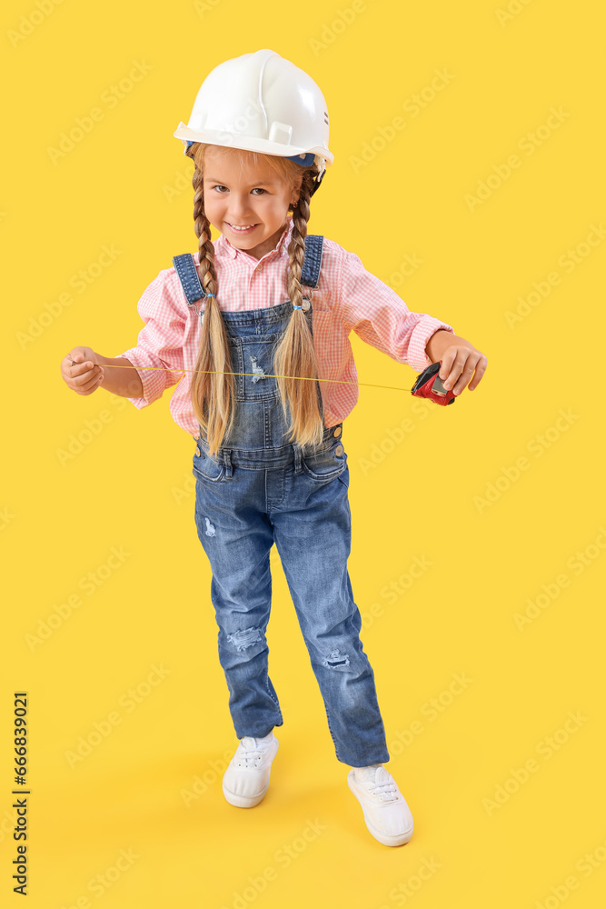 Cute little builder with measuring tape on yellow background