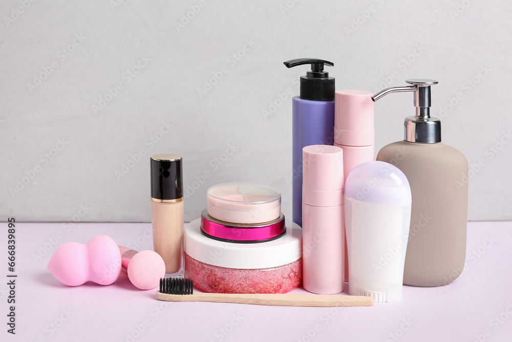 Different cosmetic products, toothbrush and makeup sponges on light background