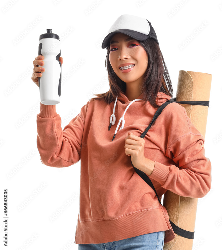 Young Asian woman in stylish hoodie with water bottle and fitness mat on white background