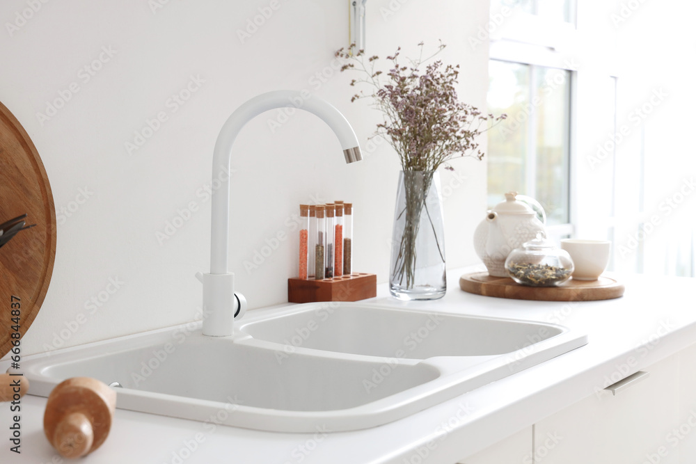 White counter with sink, condiments and dried flowers in interior of modern kitchen